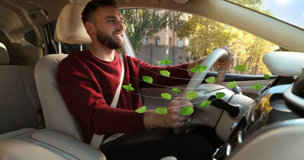 Man enjoying driving car feeling mint scent from ventilation, closeup. Air freshener