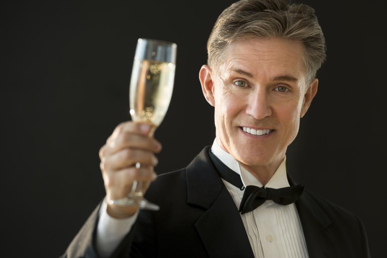 A happy older man raises a toast at a wedding | Source: Shutterstock